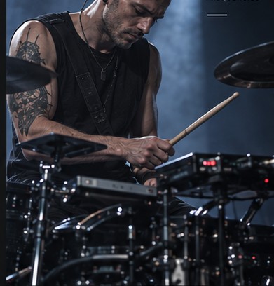 Pulse mid-performance on drums, drumstick raised, tattoos visible on his forearm.