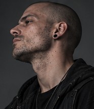 Profile portrait of Pulse, shaved head, ear piercing visible.